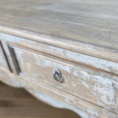 an old white wooden table with drawers and knobs