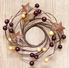 a close up of a wreath on a wooden surface with stars and berries hanging from it