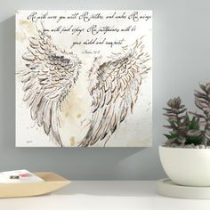 an angel wings painting on a wall above a table with a potted plant in front of it