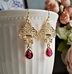 Gorgeous earrings feature gold plated brass Baroque lace filigree and faceted ruby glass drop encased in golden frame. On gold plated brass earwires These earrings are elegant and lovely for any occasion! MEASUREMENTS: Earring length: 50 mm Drop size: 40 mm Ruby drop size: (including loop): 8 X 14 mm For matching earrings, please click to this link: https://www.etsy.com/hk-en/listing/1128095371/ Purchase over $40 enjoys free shipping! Coupon code 'freeshipping1'. Free Gift Wrapping on request - Teardrop-shaped Gold Plated Filigree Jewelry, Gold Plated Filigree Teardrop Jewelry, Teardrop Filigree Jewelry For Weddings, Teardrop Filigree Wedding Jewelry, Wedding Filigree Teardrop Jewelry, Wedding Teardrop Filigree Jewelry, Ornate Dangle Jewelry, Gold Teardrop Crystal Earrings For Celebration, Elegant Red Chandelier Earrings With Intricate Design