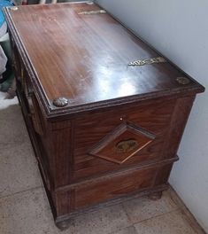 an old wooden chest with metal handles and knobs on the top, sitting in front of a white wall