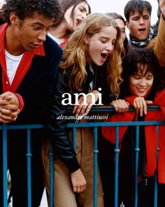 a group of young people standing next to each other near a metal fence with the words ami on it