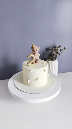 a white cake with a teddy bear on top and the number two on it's side