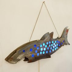 a metal fish hanging from a chain with blue lights on it's back end