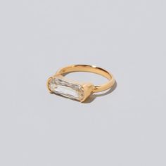 a gold ring with an oval cut diamond in the middle and a single stone on top