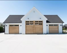 a white house with two brown garage doors