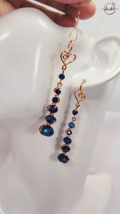 a pair of earrings with blue beads hanging from it's ear hooks on a white mannequin