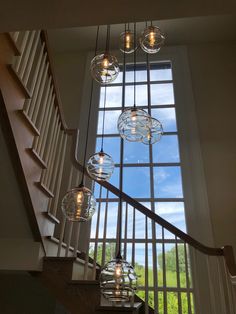 a staircase with glass globes hanging from it's sides and an open window in the background