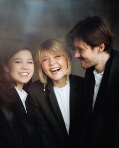 two women and a man are smiling for the camera