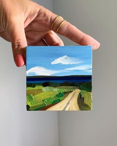 a person holding up a small piece of art that looks like a road in the sky