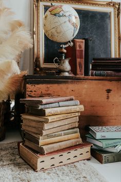 a stack of books sitting on top of a table next to a lamp and mirror