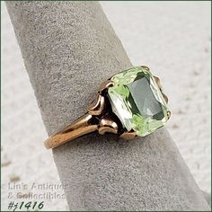 I purchased this vintage ring over 30 years ago at a local antique store that has long since closed. I fell in love with the vintage mounting and the beautiful light green color stone. Unlike most of my rings that I have listed, I actually wore this ring on a somewhat regular basis.  The green stone was listed as peridot. It measures 3/8" x 5/16" and is emerald cut. The band measures 1/16" at bottom and is marked 10k. The ring is size 7 (sorry, when I listed this ring, I listed the size in the i Collectible Green 14k Stamped Jewelry, Victorian Green Jewelry Stamped 14k, Classic Green Topaz Ring Gift, Classic Green Topaz Ring For Gift, Heirloom Green Emerald Solitaire Ring, Heirloom Green Ring For May Birthstone, Antique 14k Stamped Emerald Ring, Classic Green Emerald Ring For Collectors, Vintage Emerald Cut Birthstone Rings