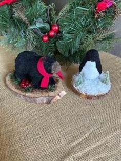 two small figurines sitting on top of a table next to a christmas tree