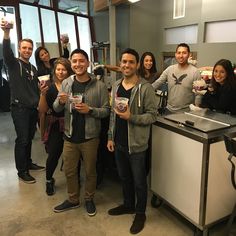 a group of people standing next to each other in front of a counter with drinks