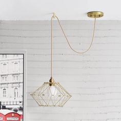 a light fixture hanging from the ceiling in a room with white brick wall and red double decker bus