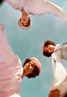 three women are standing in the air with their heads upside down and one is wearing a pink hat