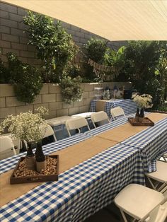 an outdoor dining area with blue and white tablecloths, potted plants and chairs