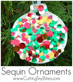 a paper plate ornament hanging from a christmas tree with colorful buttons on it