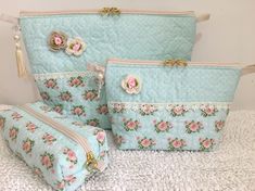 three pieces of blue fabric with pink flowers on them and two zippered purses