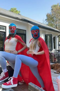 two women wearing masks and capes sitting on a porch next to each other with their feet in the air