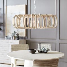 a dining room table with chairs and a chandelier hanging from the ceiling over it