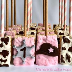 there are many pink and brown cake pops with candles in the shape of sheriff's hats