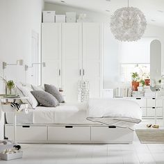 a white bedroom with lots of furniture and accessories on the floor, including a bed