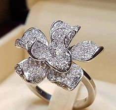 a diamond flower ring sitting on top of a box