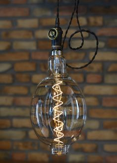 a clear light bulb hanging from a black cord in front of a brick wall with the word love written on it