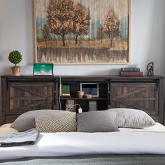 a bed with two pillows and a painting on the wall above it in a bedroom