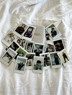 a bunch of polaroid pictures laying on top of a white bed spread with the covers pulled down