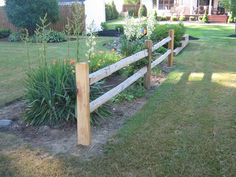 a wooden fence in the middle of a yard with flowers and plants growing on it