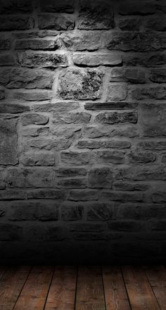 an empty room with brick wall and wooden floor, lit by a spot light in the middle