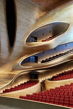 an auditorium with rows of red seats and curved walls, as well as the ceiling