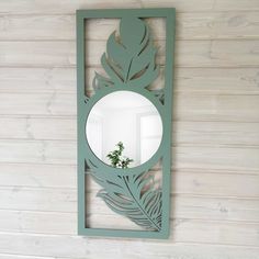 a mirror that is on the wall with a plant in it's reflection,