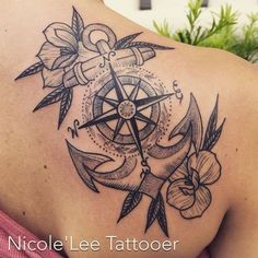 the back of a woman's shoulder with an anchor and compass tattoo