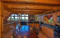 an open kitchen and dining room area with wooden walls, wood flooring and ceiling beams