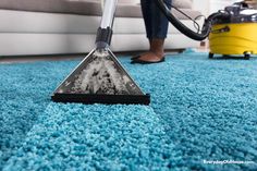 a person using a vacuum to clean a blue carpet