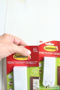 two packages of white curtains being held by a person's hand on top of them