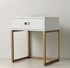 a white and gold desk with two drawers on each side, in front of a wall