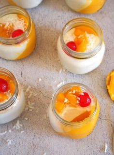 four jars filled with desserts sitting on top of a table