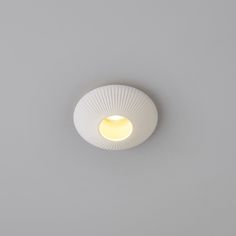 a white light that is on the ceiling in a room with grey walls and flooring