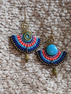 Beautiful Colombian macrame earring in contrasting pink and blues, with a blue stone as the focal point. Short and bright. These earrings are a bit heavy but the unique look is worth it! All shipping done through Canada Post, with free shipping to USA and Canada. Hippie Style Multicolor Macrame Jewelry, Adjustable Blue Bohemian Earrings, Unique Blue Macrame Jewelry, Handmade Hippie Blue Jewelry, Blue Wire-wrapped Festival Earrings, Blue Macrame Dangle Earrings, Unique Multicolor Macrame Jewelry, Blue Dangle Earrings With Macrame, Blue Wire Wrapped Earrings For Festival