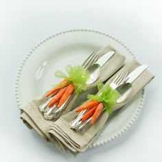 two carrots wrapped in green ribbon sit on a plate with silverware and forks