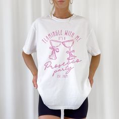 *Sold separately Get ready to pop the bubbly and unwind in style with our exclusive PJs & Prosecco Bachelorette Shirts! These chic and comfy tees are the ultimate addition to any bachelorette party, ensuring you and your crew are dressed to impress whether you're sipping prosecco at brunch or having a cozy night in. - 100% ring-spun cotton - Medium fabric (6.1 oz/yd² (206.8 g/m - Relaxed fit - Sewn-in twill label PRINT METHOD:  We use Direct-to-garment printing method for this product. CARE INST Fitted Crew Neck Shirt For Bachelorette Party, Holiday Party T-shirt With Short Sleeves, White Fitted T-shirt For Bachelorette Party, White Fitted Shirt For Bachelorette Party, White Fitted Top For Bachelorette Party, Fitted White Tops For Bachelorette Party, Summer Fitted T-shirt For Bachelorette Party, Fitted T-shirt For Summer Bachelorette Party, White Summer Top For Hen Party