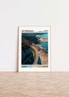 an australian travel poster hangs on the wall next to a wooden floor in front of a white wall