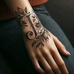 a woman's hand with a tattoo on it and the letter j in floral designs