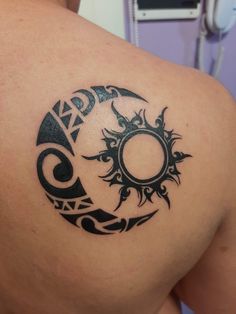 a tattoo on the back of a man's shoulder with an image of a sun and moon