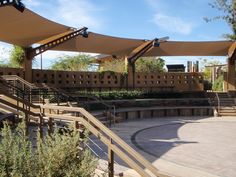 an outdoor area with stairs, benches and shade sails on the roof over looking trees