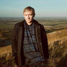 a man standing on top of a grass covered hillside